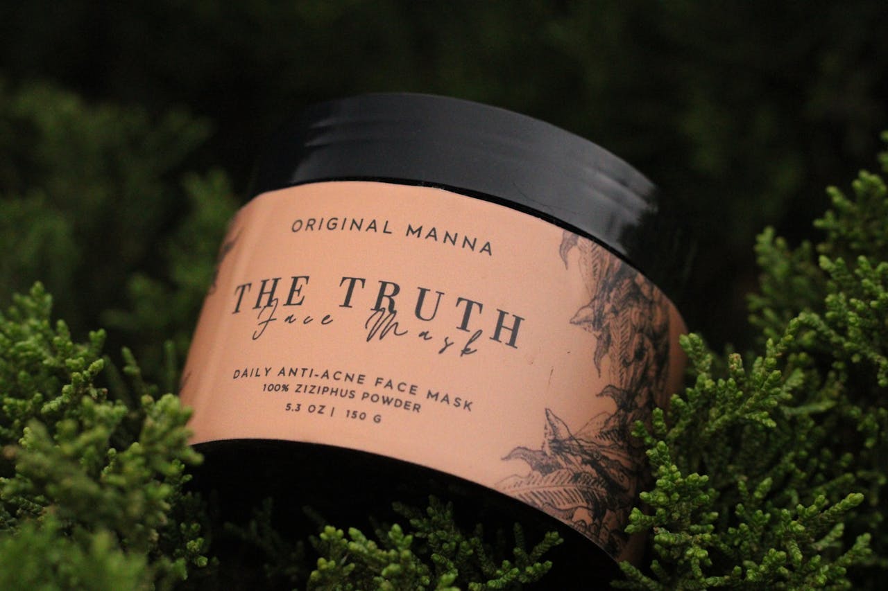 Face mask container amidst lush green foliage, emphasizing natural skincare.
