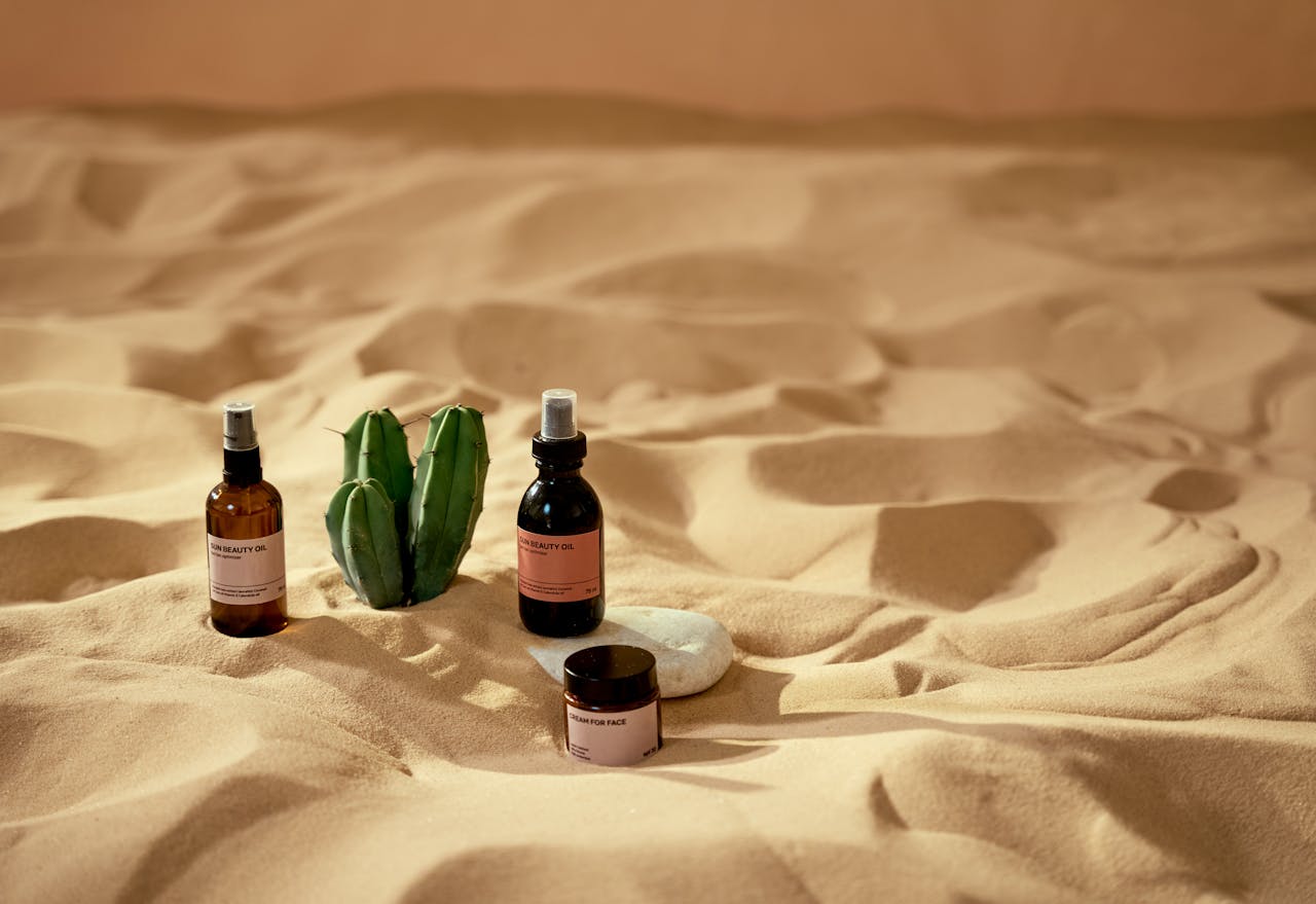 Elegant skincare bottles on sand with aloe, highlighting natural beauty and serenity.
